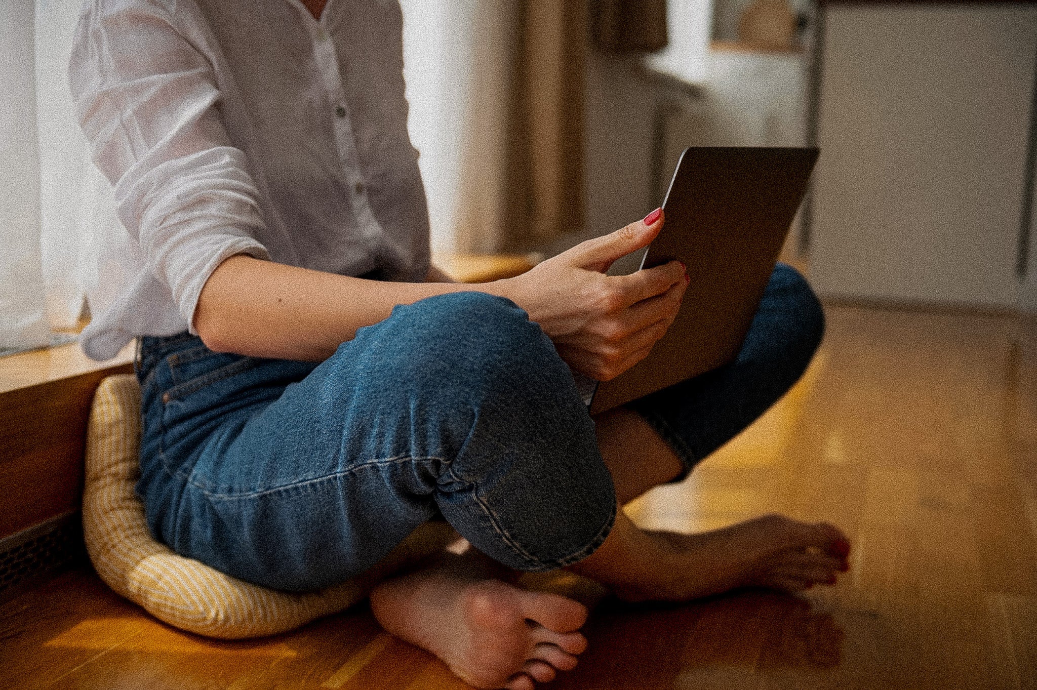 Zenska osoba koristi laptop dok je u lotus polozaju